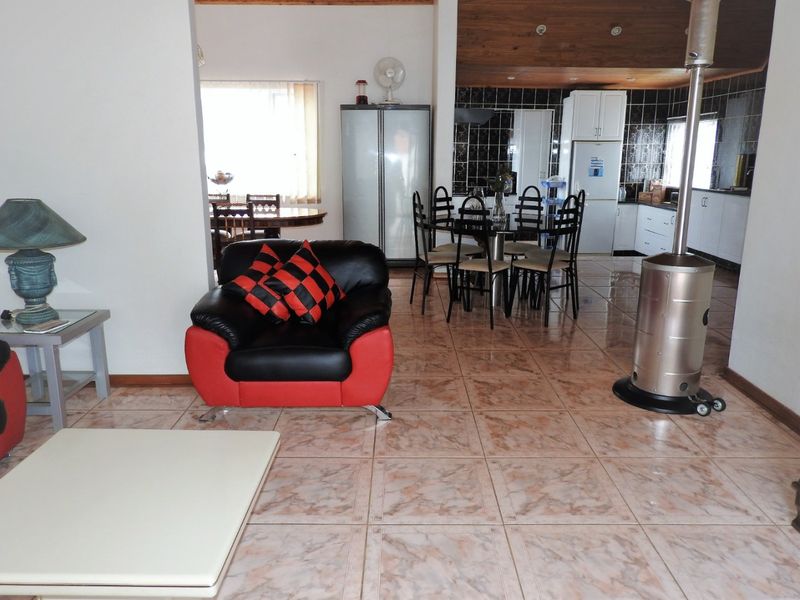 Open plan living and dining area featuring tiled flooring and a wooden ceiling, seamlessly connected to a functional kitchen space.