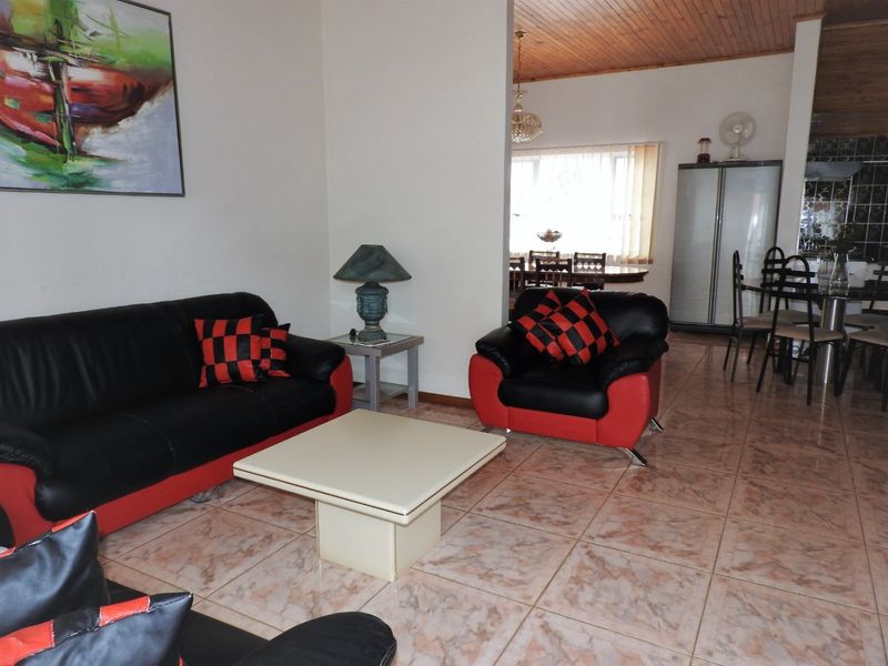 Open plan living and dining area featuring tiled flooring and a timber ceiling, with an adjacent kitchen space.