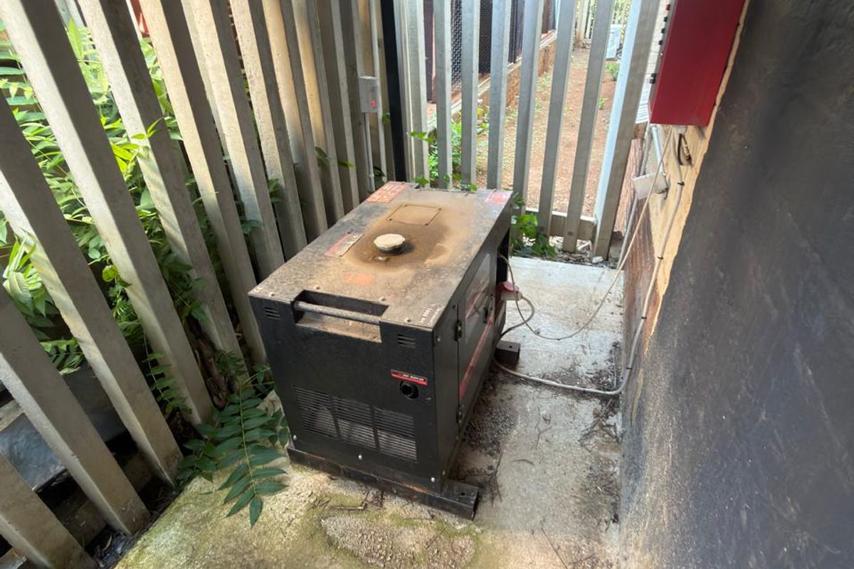 Outdoor utility area featuring a covered concrete pad with a generator and perimeter fencing.