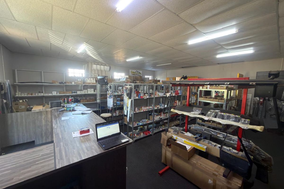 Commercial storage and retail space featuring industrial shelving units, a service counter, and fluorescent overhead lighting.