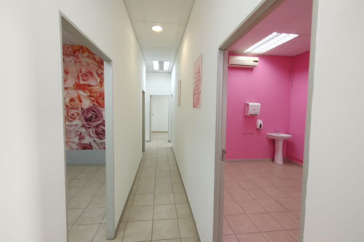 A commercial hallway providing access to multiple rooms, including a washroom area featuring a pedestal sink and wall-mounted air conditioning unit.