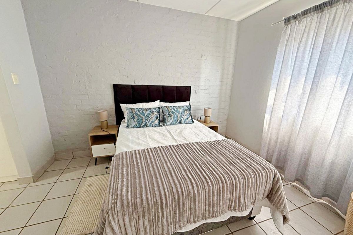 A bedroom featuring tiled flooring and a textured painted brick feature wall, providing a neutral foundation for interior design.
