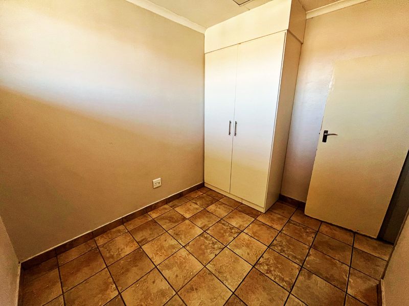A clean, empty bedroom featuring tiled flooring and a built-in wardrobe, offering a neutral space ready for personalization.