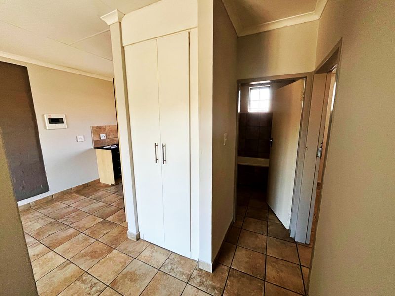 A functional hallway featuring tiled flooring and a built-in storage cupboard, providing access to adjacent living and bathroom areas.