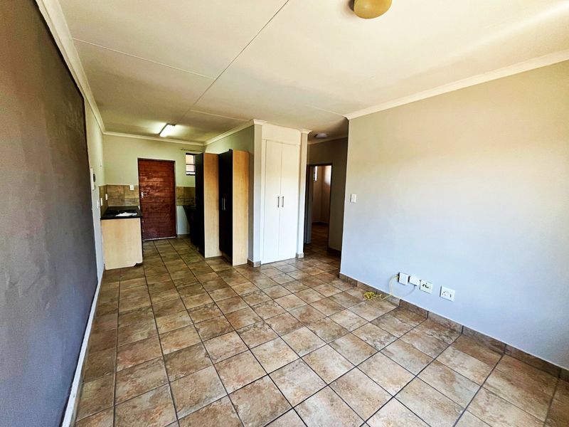 An open-plan living and kitchen area featuring tiled flooring, built-in cabinetry, and neutral wall finishes, offering a versatile space for living and dining.