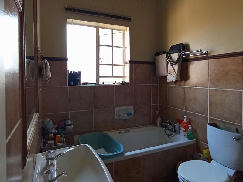 A dated bathroom featuring a bathtub, toilet, and washbasin with tiled walls, requiring cosmetic updates to improve its overall condition and appeal.