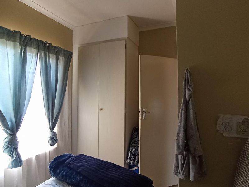 A bedroom featuring built-in cupboards and neutral wall finishes, offering a functional space with natural light.