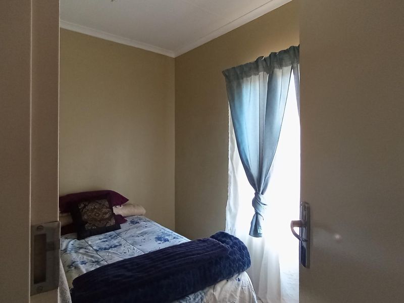 A compact bedroom featuring neutral wall paint and a window with natural light, providing a functional space for rest.
