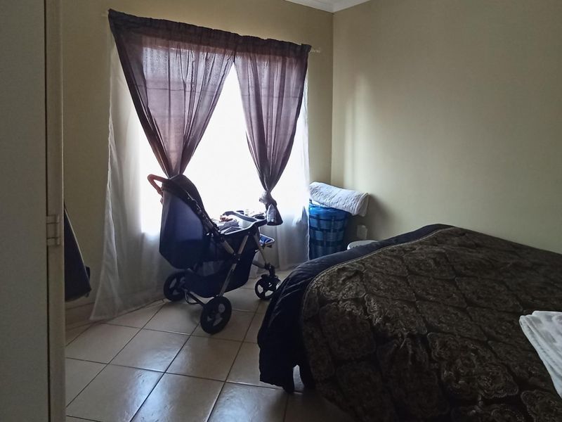 A bedroom featuring tiled flooring and a window with installed curtain rods, providing a functional space for rest.