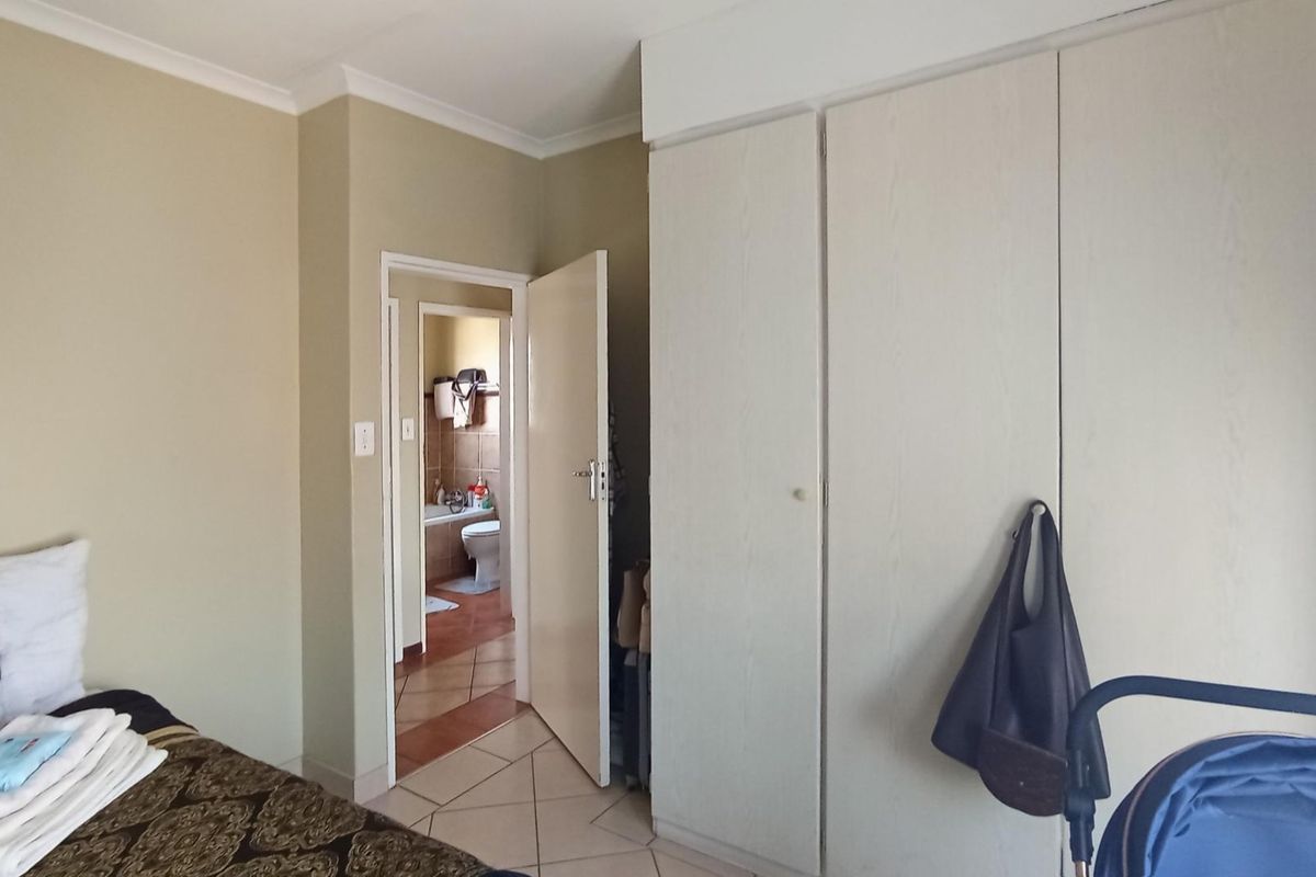 Bedroom featuring built-in cupboards and tiled flooring, with an adjoining bathroom visible through the doorway.