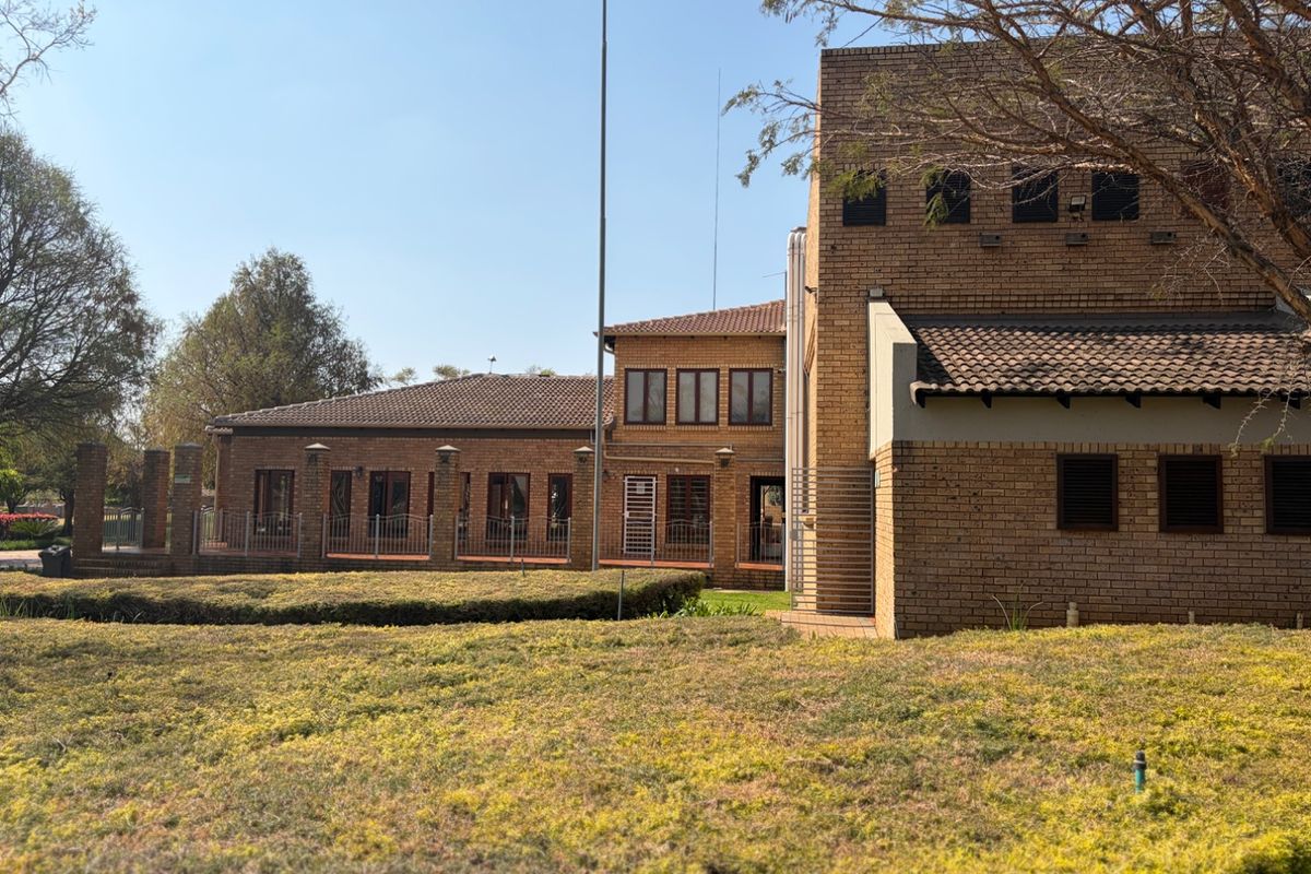 A view of the rear exterior of the apartment building featuring face brick construction, tiled roofing, and well-maintained surrounding garden areas.