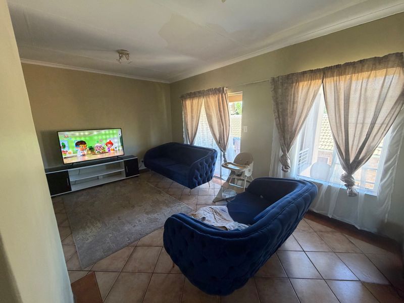 A living room featuring tiled flooring, ceiling coving, and a sliding glass door leading to an outdoor area.