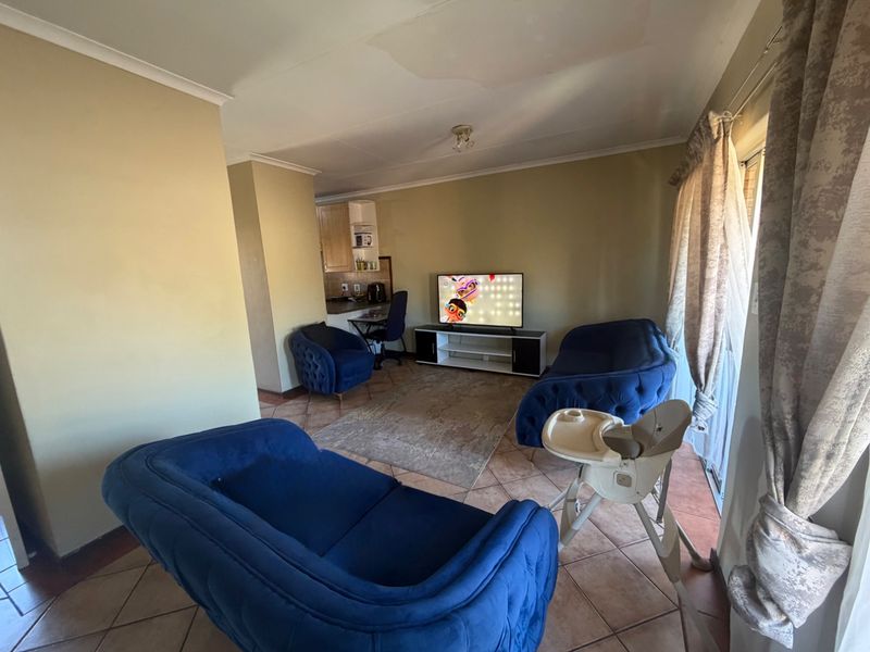 Open plan living area featuring tiled flooring and a compact kitchen corner, with visible ceiling water damage requiring attention.