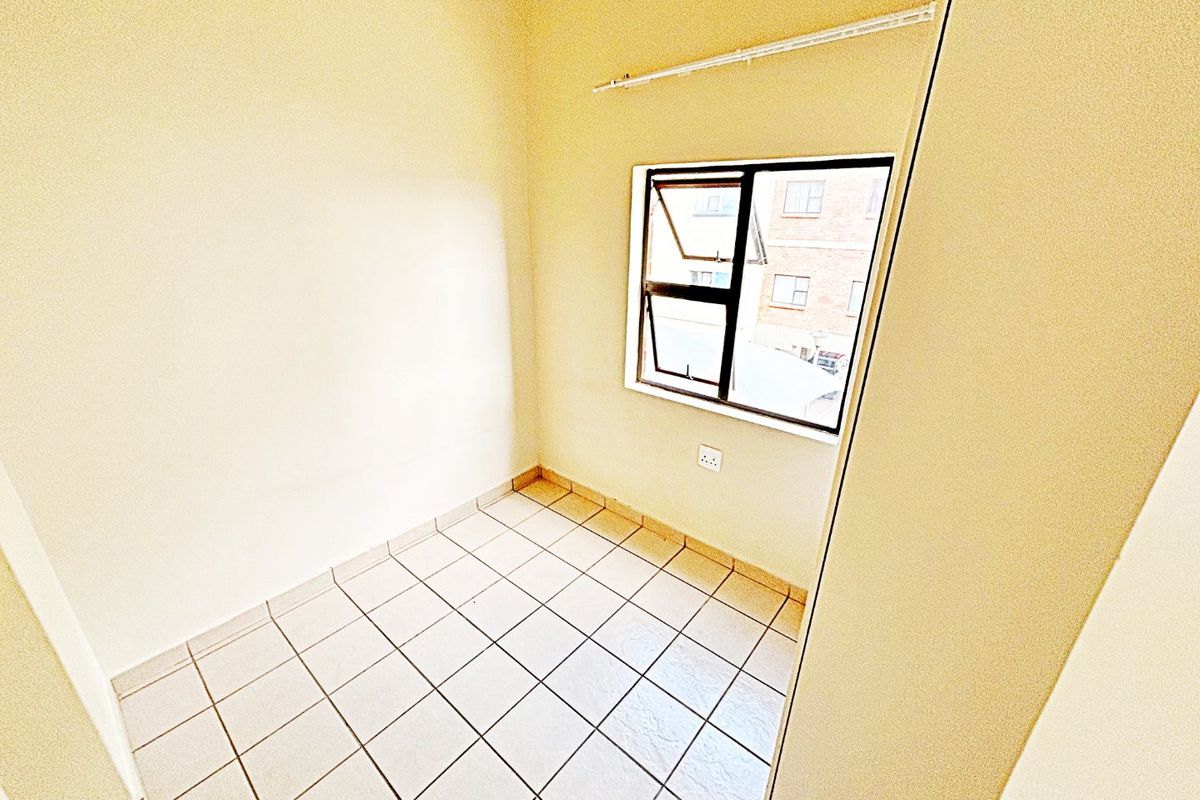 A compact, empty bedroom featuring tiled flooring and a top-hung window, providing a neutral space ready for personalization.