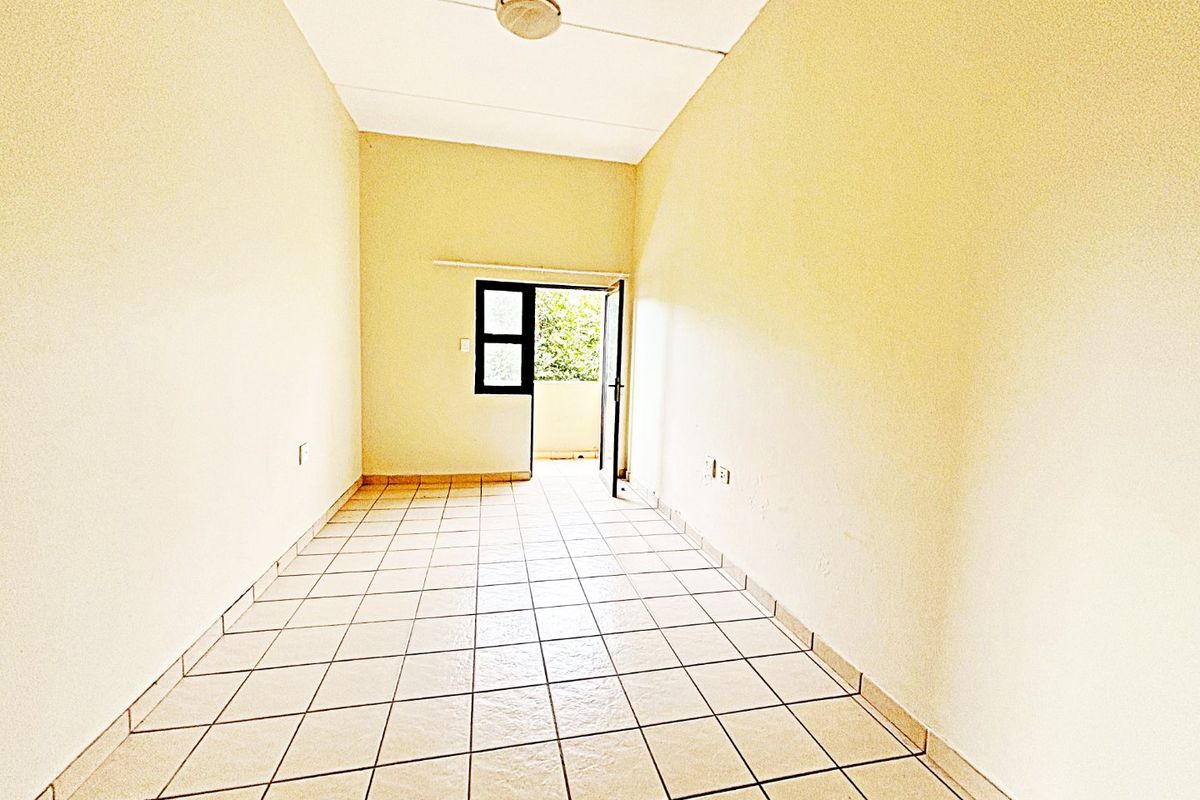 An empty, neutrally painted living area featuring tiled flooring and direct access to an outdoor balcony space.