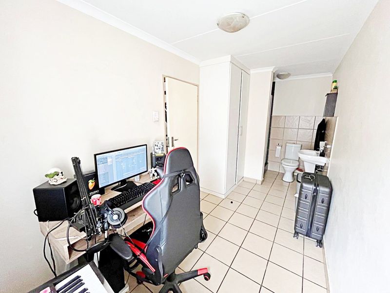A bedroom featuring tiled flooring, a built-in wardrobe, and an open-plan en-suite bathroom with a toilet and basin.
