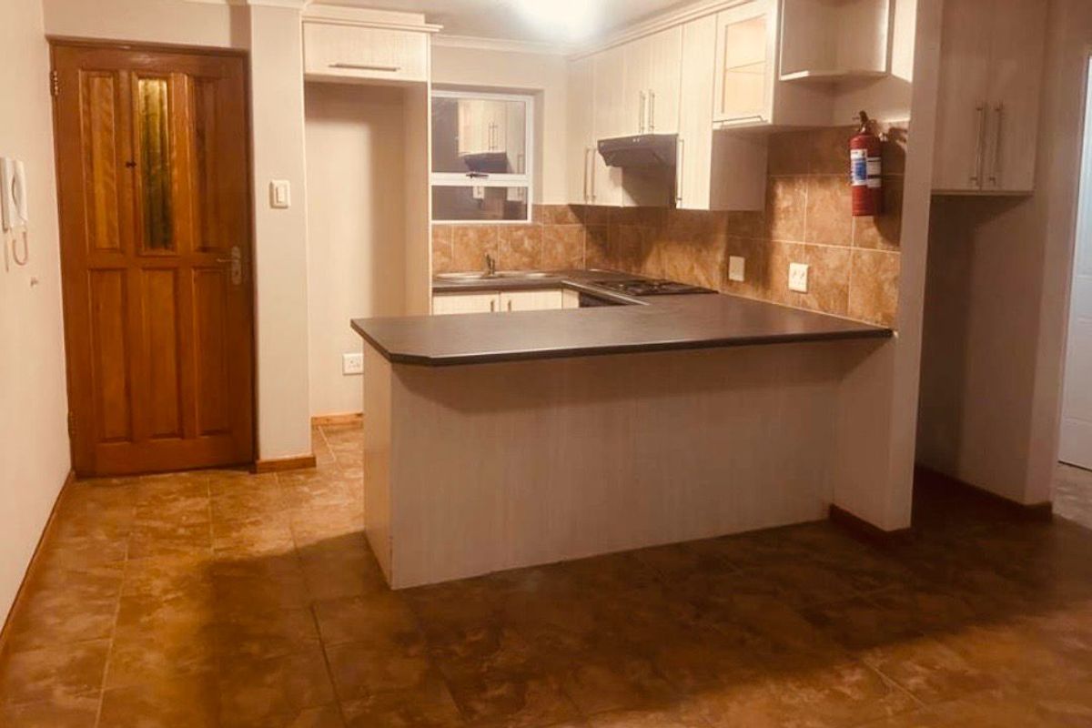 A functional kitchen featuring built-in cabinetry, laminate countertops, a tiled backsplash, and tiled flooring, offering a practical layout for daily use.