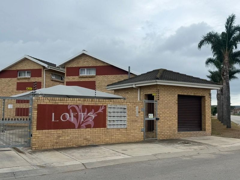 Front exterior view of the townhouse complex entrance, featuring face brick construction, secure gated access, and integrated post boxes.