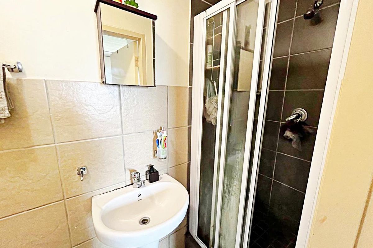 A functional bathroom featuring a pedestal basin, wall tiling, and a shower enclosure with a sliding door.