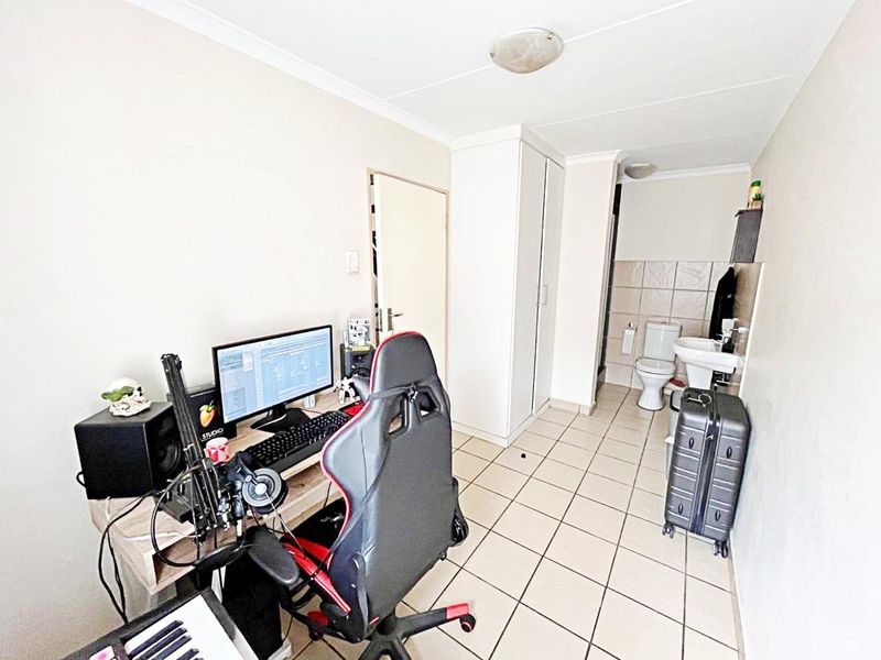 A bedroom featuring tiled flooring, a built-in wardrobe, and an open-plan en-suite bathroom with a toilet and basin.