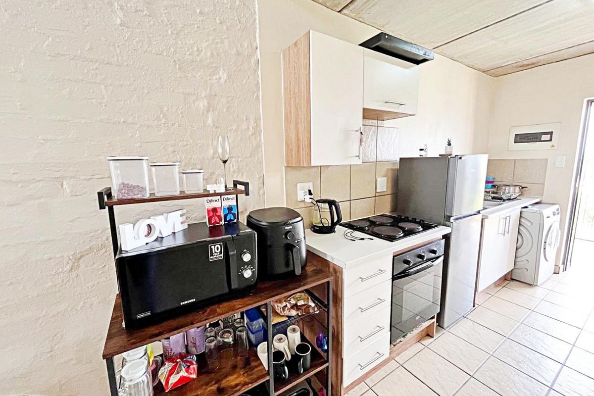 Compact kitchen featuring built-in cabinetry, electric hob, oven, extractor fan, and tiled flooring with a functional layout.