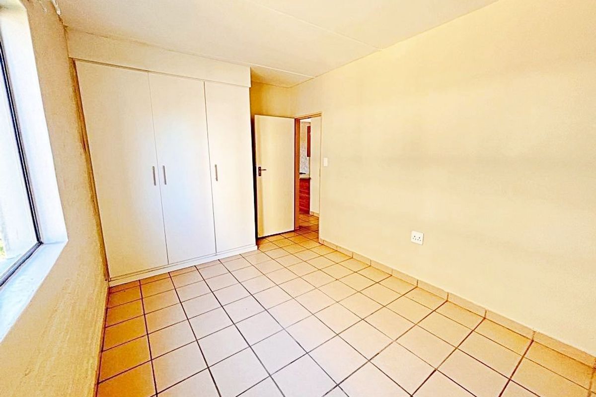 An empty bedroom featuring tiled flooring and a built-in wardrobe, offering a blank canvas for potential interior updates.