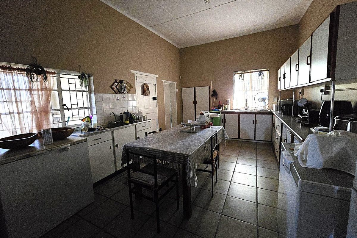 Spacious farm-style kitchen featuring extensive built-in cabinetry, tiled flooring, and a functional layout with ample counter space and natural light.