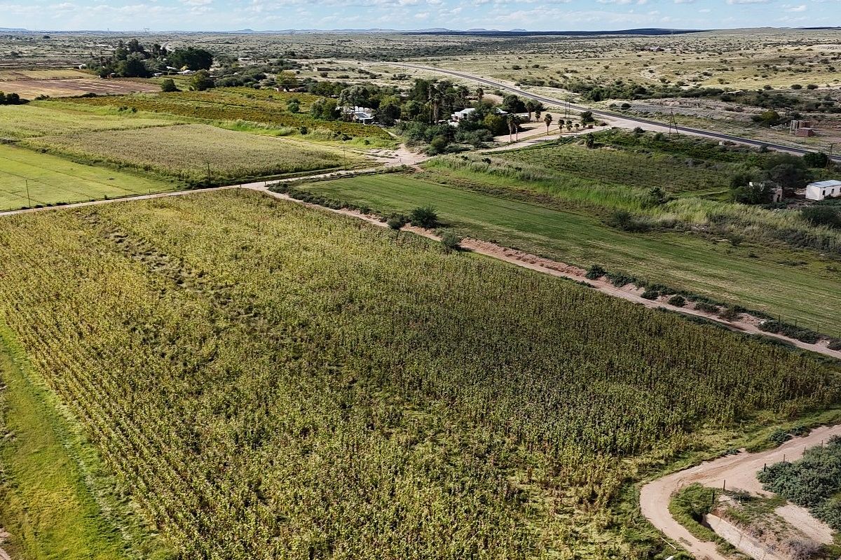 An aerial view of the expansive farm property featuring cultivated agricultural fields, internal access roads, and surrounding rural landscape.