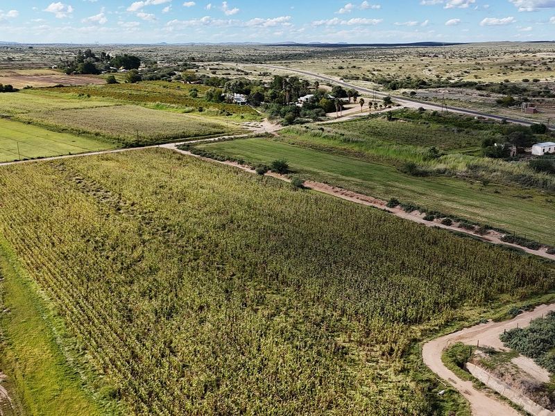 An aerial view of the expansive farm property featuring cultivated agricultural fields, internal access roads, and surrounding rural landscape.