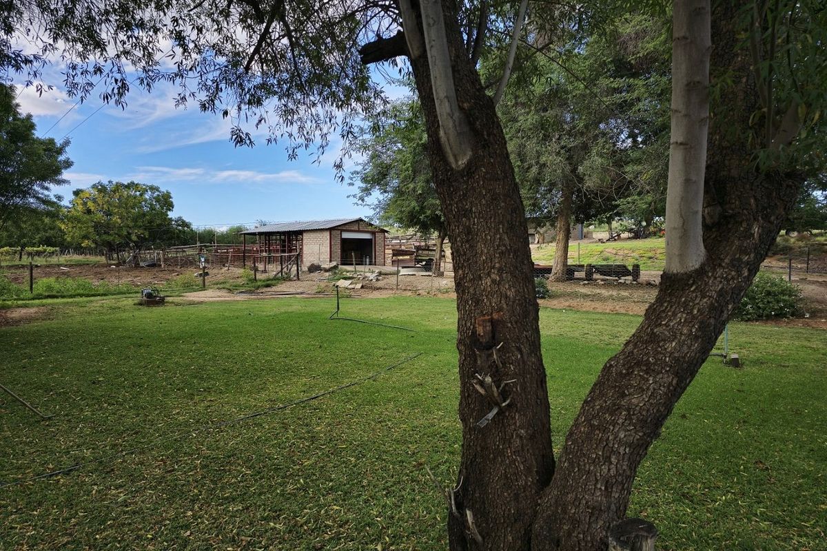 A view of the farm grounds featuring a well-maintained lawn, perimeter fencing, and a functional outbuilding structure in the background.