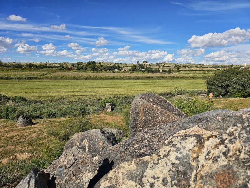 A scenic landscape view overlooking expansive agricultural fields and natural rock formations on the farm property.