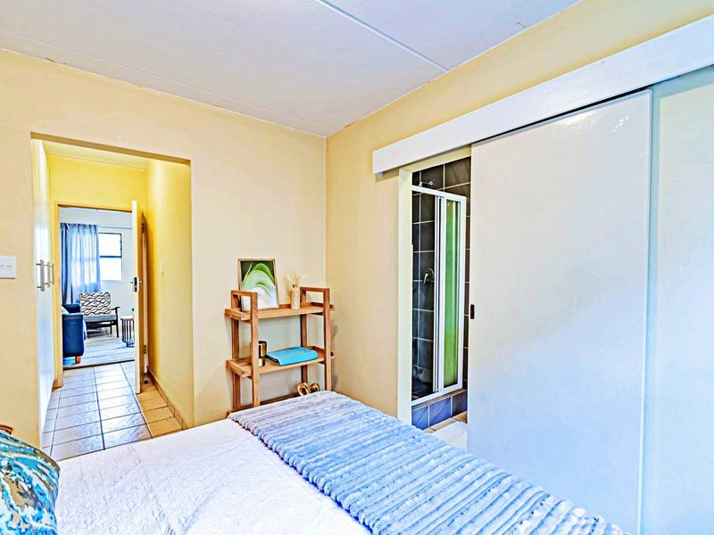 Bedroom featuring a sliding door leading to an en-suite shower, with tiled flooring visible in the adjacent hallway.