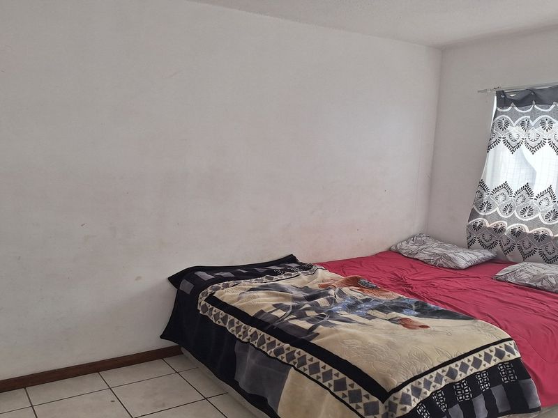 A bedroom featuring ceramic floor tiles and a window with a curtain rod, requiring minor cosmetic updates to the wall finishes.