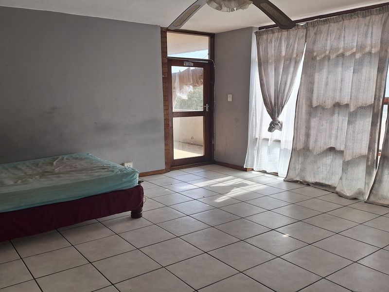 A bedroom featuring tiled flooring, a ceiling fan, and direct access to an outdoor balcony through a glass door.