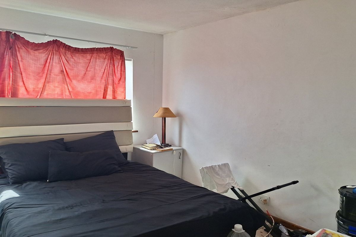 A bedroom featuring a window with natural light, requiring cosmetic updates to the wall finishes to improve the overall aesthetic.