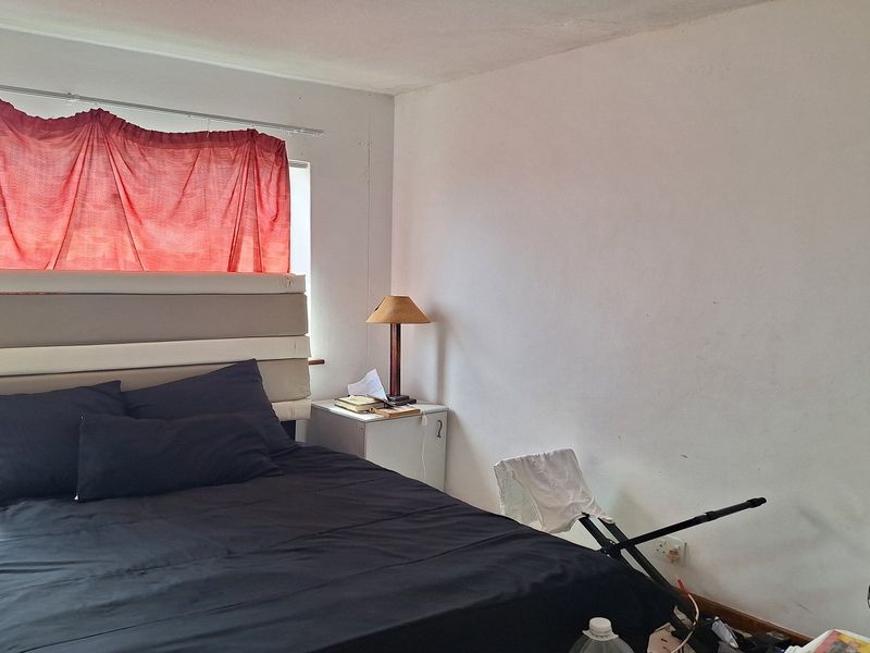 A bedroom featuring a window with natural light, requiring cosmetic updates to the wall finishes to improve the overall aesthetic.