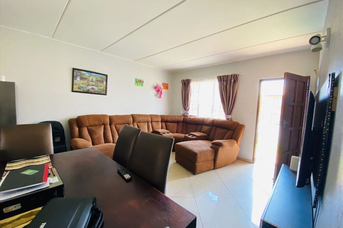 A living room area featuring tiled flooring and a panel ceiling, with direct access to the exterior.