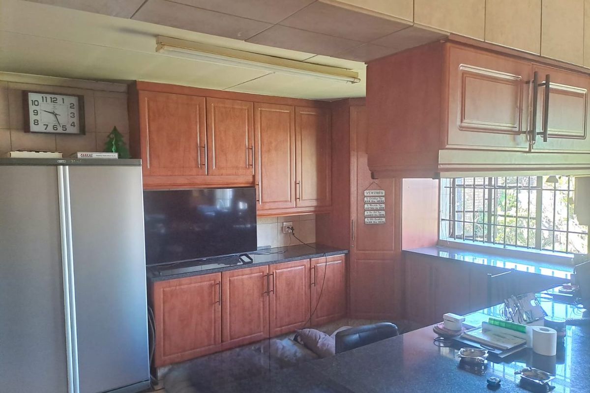 A functional kitchen featuring wood-finish cabinetry, granite countertops, and security bars on the window, offering a traditional layout with ample storage space.