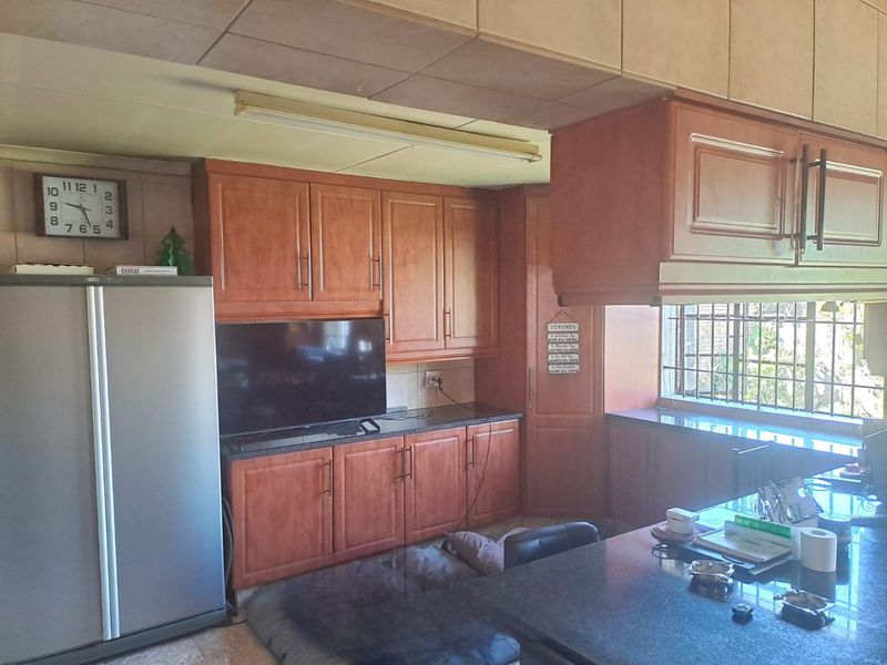 A functional kitchen featuring wood-finish cabinetry, granite countertops, and security bars on the window, offering a traditional layout with ample storage space.