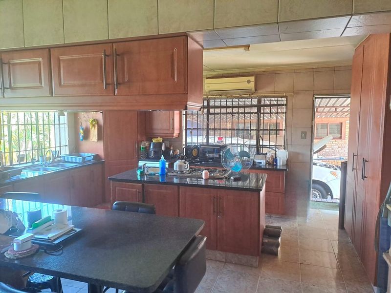 A functional kitchen featuring dark wood cabinetry, granite countertops, a gas hob, and tiled flooring, with direct access to the exterior.