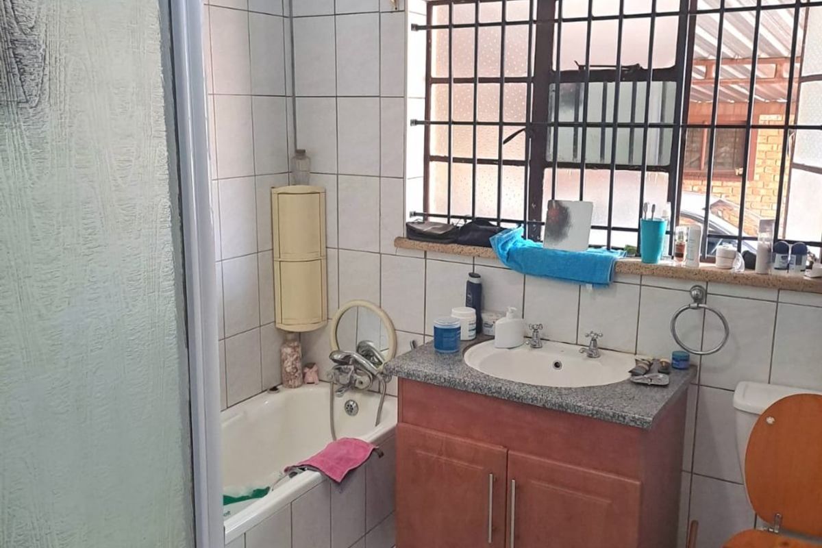 A functional bathroom featuring a shower enclosure, bathtub, vanity cabinet with basin, and toilet, finished with tiled walls and floors.