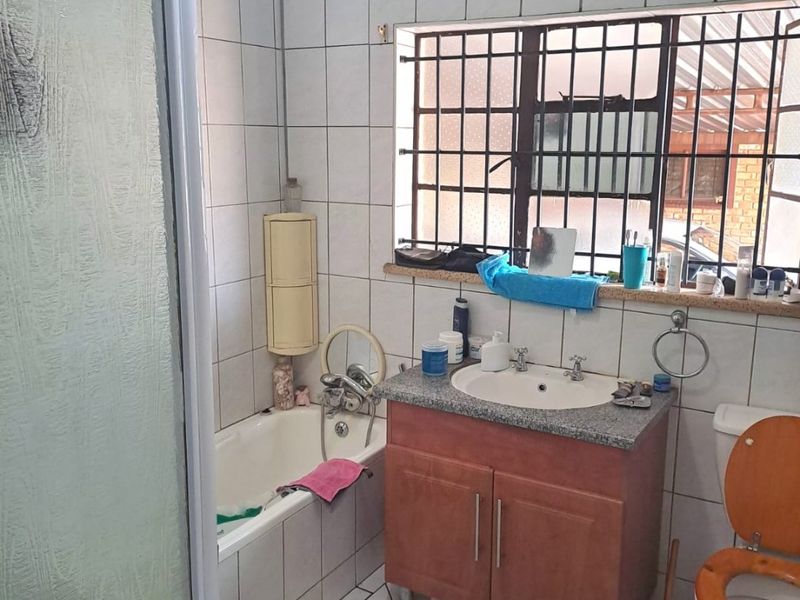 A functional bathroom featuring a shower enclosure, bathtub, vanity cabinet with basin, and toilet, finished with tiled walls and floors.