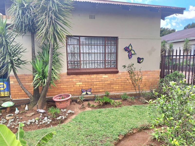 Front exterior view of the house featuring a brick facade, security bars on the windows, and a small front garden area.