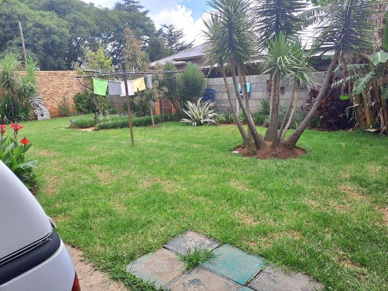 A private rear garden featuring a well-maintained lawn, mature landscaping, and secure perimeter walling.