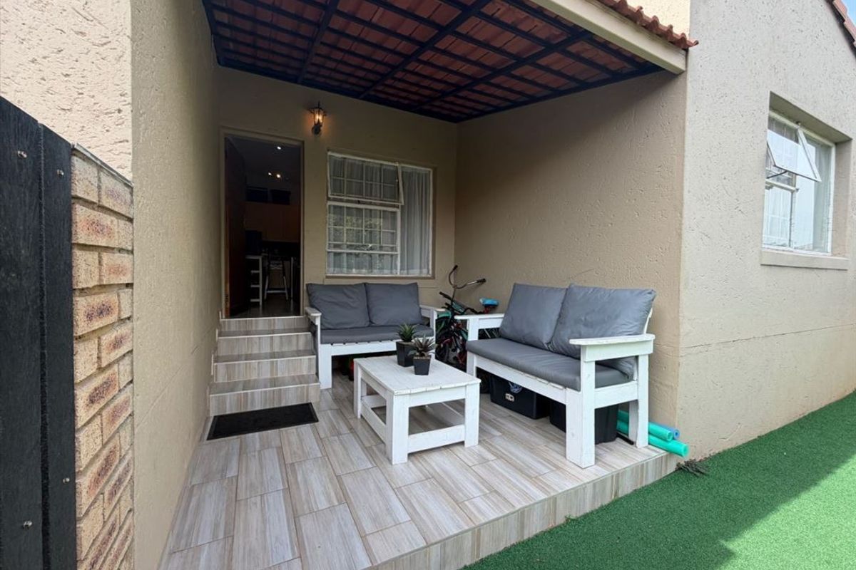 A covered patio area featuring tiled flooring and direct access to the interior, providing a functional outdoor space for relaxation.