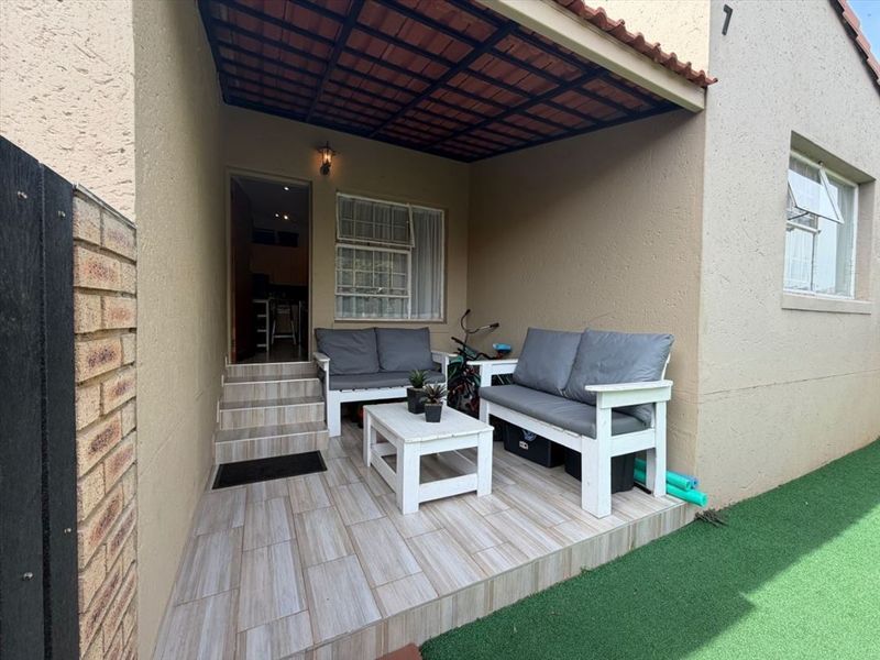 A covered patio area featuring tiled flooring and direct access to the interior, providing a functional outdoor space for relaxation.