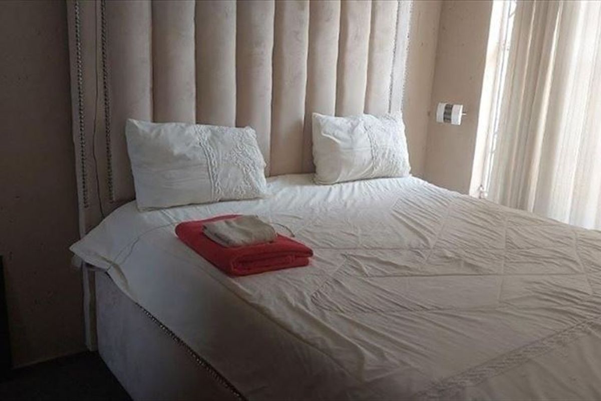 A bedroom featuring a large upholstered headboard and natural light from the adjacent window.
