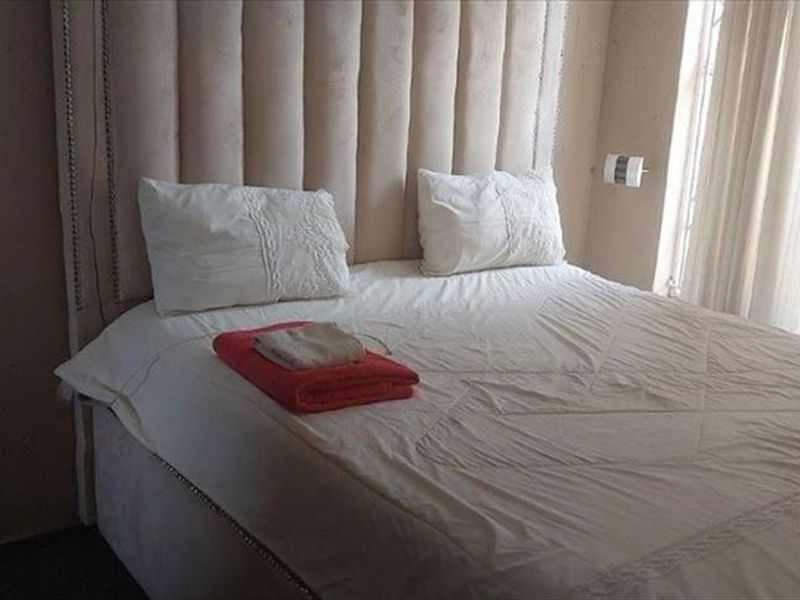 A bedroom featuring a large upholstered headboard and natural light from the adjacent window.