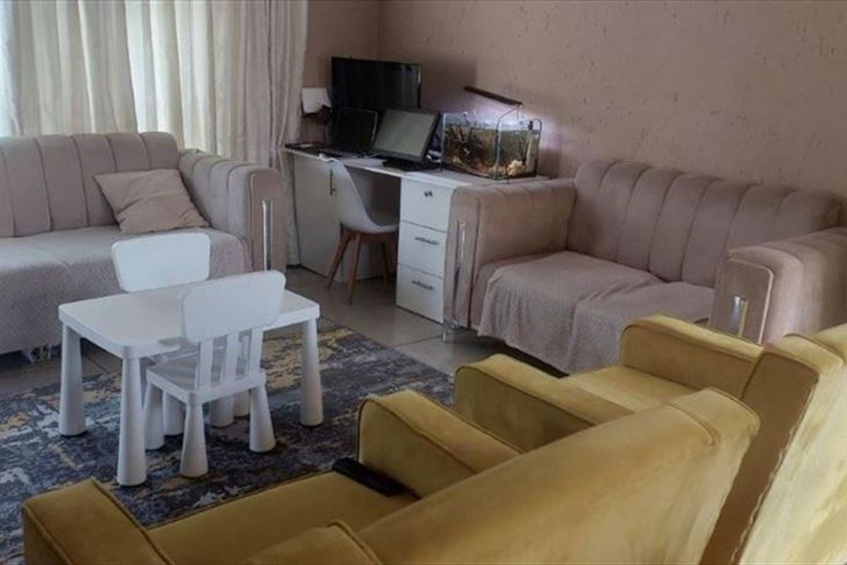 A living room area featuring tiled flooring and a sliding glass door, providing access to natural light.