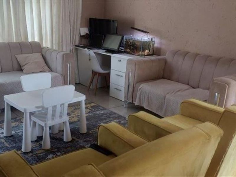 A living room area featuring tiled flooring and a sliding glass door, providing access to natural light.